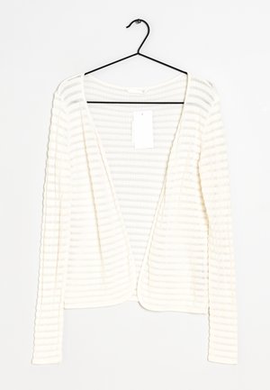 White, ribbed cardigan with long sleeves and an open front, hanging on a black hook. Tag attached inside neckline. Soft texture.