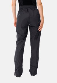 Pantalons noirs imperméables avec une texture légère et lisse. Équipés d'une taille élastique et de réglages en Velcro au niveau des chevilles.