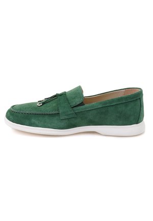 Groene suede instapper met een witte zool, voorzien van een ronde neus, stikseldetails en een decoratieve lederen band over de wreef.