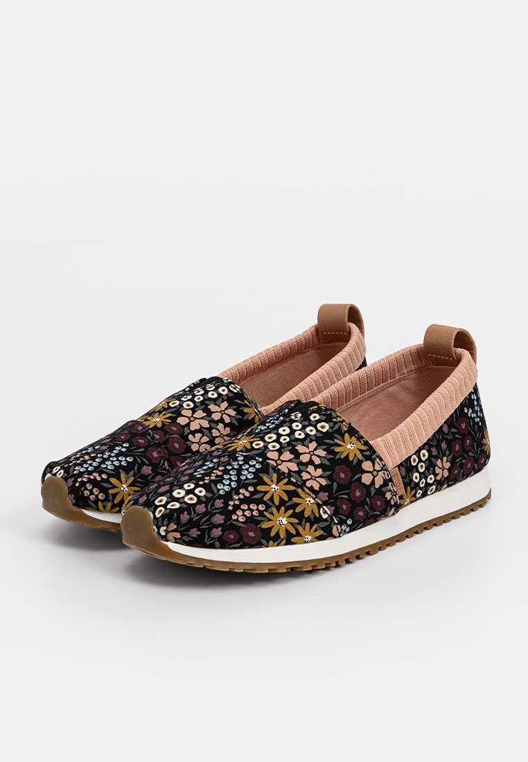 Zapatillas de tela con estampado floral, parte superior de tela negra, detalles elásticos en rosa suave y suela de goma blanca.