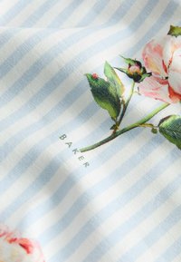 Tissu rayé bleu clair et blanc avec une rose rose imprimée et des feuilles vertes, avec le texte "BAKER" en dessous de la fleur.