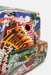 Kompakte Kamera mit einem mehrfarbigen Grafikmuster, das Flammen, Skater-Logos und auffälligen Text zeigt. Enthält Tasten und einen Ladeanschluss.