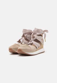 Zapatillas trenzadas beige con correas elásticas, parte superior de punto texturizado y tacón en cuña. La entresuela blanca y la suela de goma ofrecen tracción.