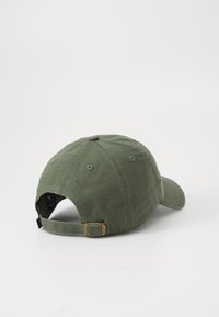Casquette en coton vert avec une visière incurvée, sangle arrière ajustable en métal et détails de couture. Tissu texturé et six œillets de ventilation.