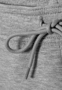 Κοντινή λήψη της μέσης ενός γκρι παντελονιού φόρμας με δεμένο γκρι κορδόνι που έχει δέσει σε κόμπο.