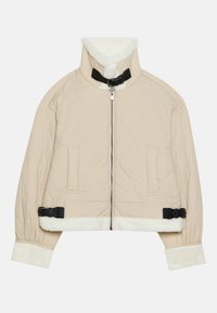 Beżowa pikowana kurtka z wysokim kołnierzem, czarnym zapięciem na klamrę oraz białym futerkiem przy mankietach i na dole. Dwie przednie kieszenie.