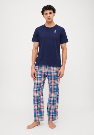 T-shirt en coton bleu marine avec un petit motif brodé, associé à un pantalon de pyjama à carreaux multicolores dans les teintes vert, bleu, jaune et violet.