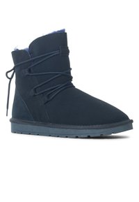 Stivaletto in suede blu navy con punta arrotondata, tessuto texturizzato, design con lacci e una morbida fodera in pelliccia blu al colletto. Suola piatta in gomma.