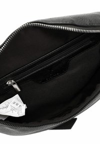 Interno di una borsa in pelle nera con una texture liscia, dotata di una tasca con zip e etichette in tessuto. Chiusura lampo in argento.