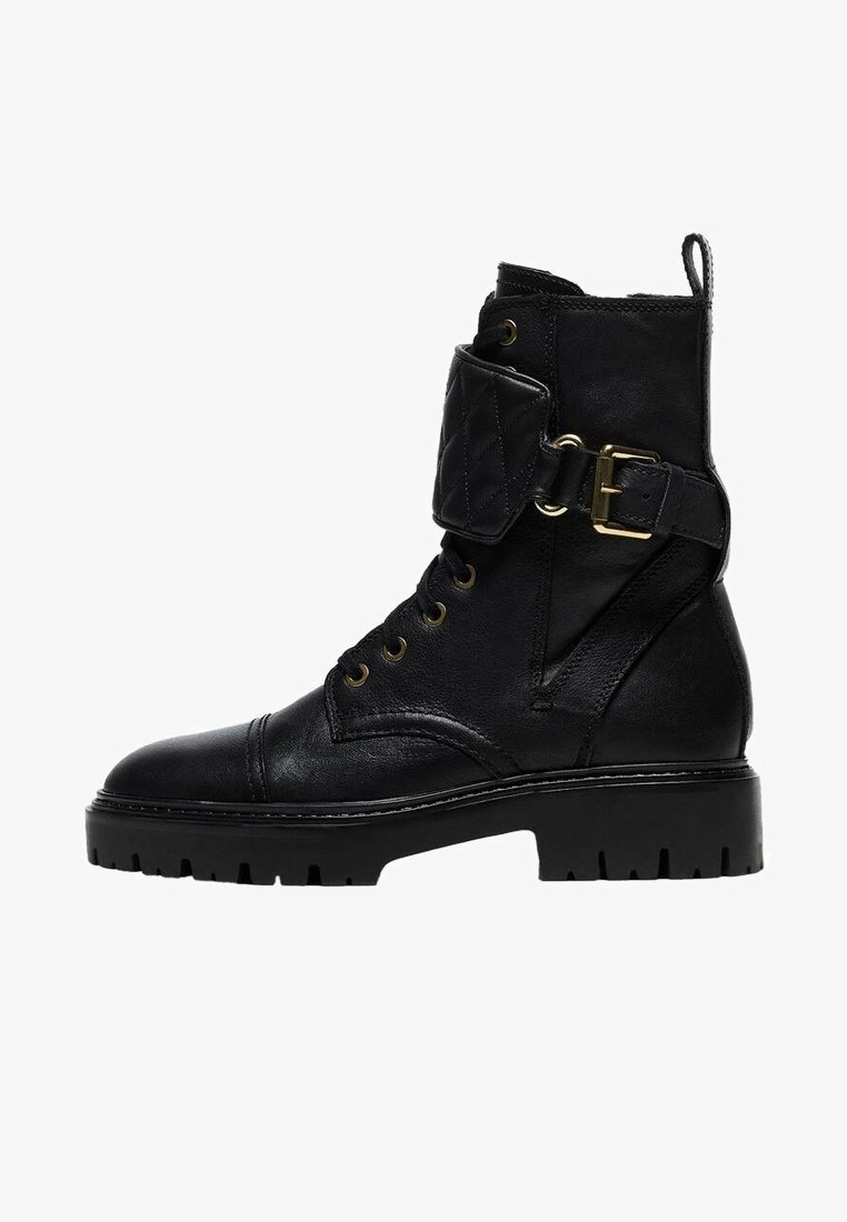 Czarne skórzane botki za kostkę z złotym wykończeniem, pikowaną tasiemką wokół kostki, okrągłym noskiem oraz masywną podeszwą z głębokim bieżnikiem.