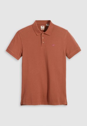 Rostfarbendes Poloshirt aus Baumwolle, mit Kragen, drei Knöpfen und einem kleinen roten Logo auf der linken Brust. Kurzärmlig, einfarbige Textur.