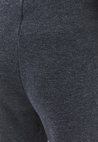 Donkergrijze legging gemaakt van gestructureerde stof, met een gladde afwerking en een nauwsluitende pasvorm, geschikt voor casual of sportief gebruik.