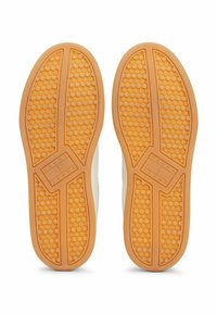 Suola di una sneaker, caratterizzata da una gomma arancione testurizzata con motivi circolari. Logo del marchio impresso su una sezione rettangolare.