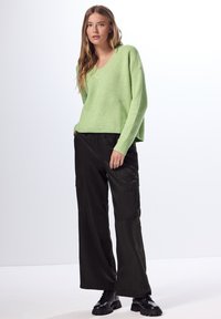 Ljusgrön ribbad virkadräkt med V-ringning, ihop med svarta vida cargo-byxor och svarta kraftiga skor. En enkel och avslappnad outfit.