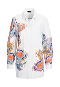 Chemise en coton blanche arborant de vifs motifs floraux en bleu, orange et vert sur les manches, avec un col classique et un design à boutonner.