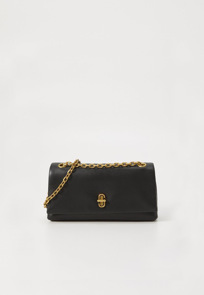 Clutch de pele preta com uma alça em corrente dourada e fecho dourado, colocado sobre um fundo branco liso.
