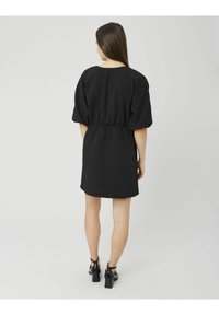 Robe noire texturée avec manches courtes bouffantes, taille cintrée et coupe décontractée. Le matériau présente un motif subtil et une finition lisse.