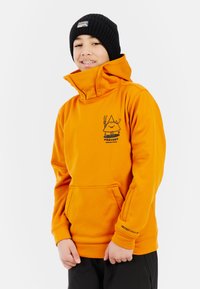 Oranžová mikina s kapucňou a vysokým golierom, predná vrecko a čierny grafický dizajn. Nosená s čiernou pletenou čiapkou. Hladká tkanina.