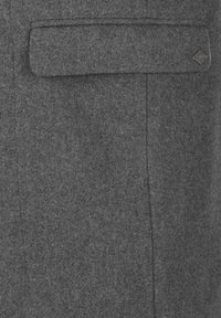 Tela de fieltro gris con una textura suave, que presenta un bolsillo de solapa y un acento de metal en el lado derecho, creando un diseño minimalista.
