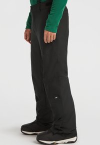 Zwarte sneeuwbroeken met een recht model, gemaakt van duurzaam materiaal, voorzien van voorzakken en een logo patch nabij de zoom.