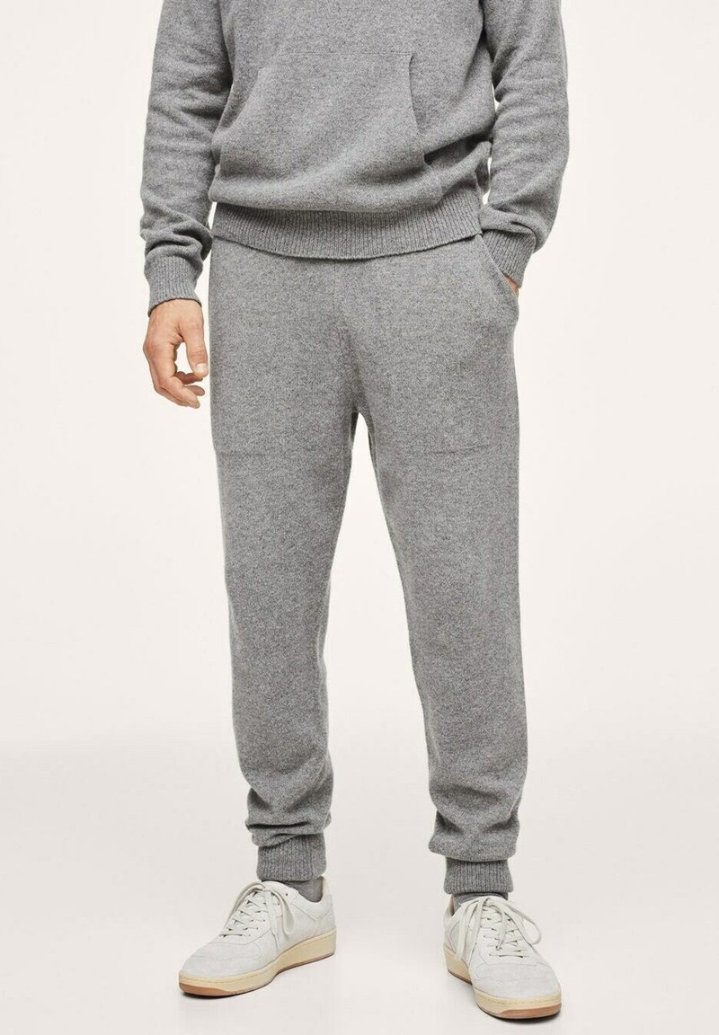 Grijze gebreide sweatshirt met bijpassende broek, voorzien van geribbelde boorden, een relaxte pasvorm en zijzakken. Afgemaakt met witte sport schoenen.