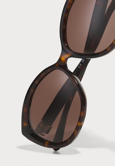 Brown tortoiseshell sunglasses with large rounded lenses and a sleek plastic frame, featuring dark brown lenses and slim arms.