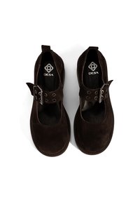 Dunkelbraune Wildlederschuhe mit runder Zehenform, vorderem Riemen und metallenen Schnallenakzenten. Glattes Innenfutter und flaches Sohlen-Design. Sichtbares Markenlogo.