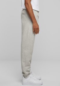 Lysegrå sweatsbukser lavet af blødt stof, med en tapered pasform, elastisk talje og ribbede manchetter, parret med hvide sneakers.