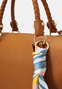 Braune Handtasche mit glatter Lederstruktur und geflochtenen Griffen. Enthält einen dekorativen, mehrfarbigen Schal, der an einem goldenen Ring befestigt ist.