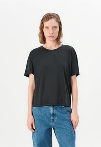 Svart kortermet t-skjorte med rund hals, laget av myk stoff. Kombinert med høyt midjebånd blå denimjeans.