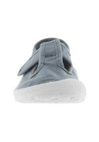 Zapato de tela azul claro con suela de goma blanca, que cuenta con una correa ajustable y lados abiertos para ventilación y facilidad de uso.