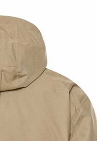 Beige jakke med hætte, lavet af tekstureret stof, med synlige sømme langs skuldrene og nakkeområdet.