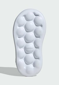 Biely gumený podrážka obuvi s okrúhlymi, bublinkovitými prehlbňami pre textúru. Logo "adidas" vtláčané blízko dolného stredu. Hladké hrany.