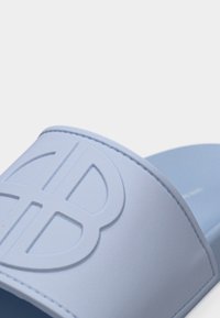 Γαλάζιο σανδάλι με φαρδιά λωρίδα που φέρει ανάγλυφο, στυλιζαρισμένο λογότυπο και λείο πέλμα.