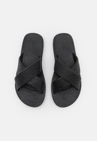 Svarta sandaler med korsade, texturerade remmar och en slät sula. Remmarna har ett vävt mönster, vilket ger flexibel komfort.