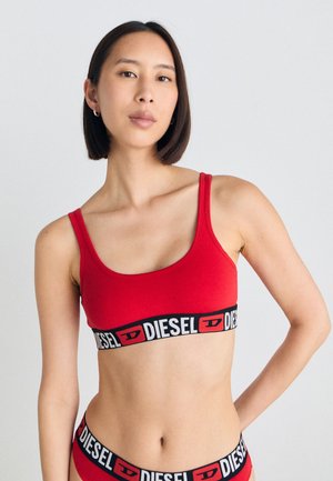 Röd bomulls-bralette med tunna band, med en svart kant med "DIESEL"-logotypen. Slät textur och figurnära design.