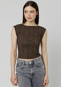 Top court en imprimé léopard brun avec des manches courtes, design ajusté et tissu texturé, associé à un jean en denim gris taille haute.