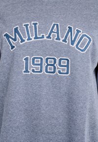 Šedá bavlnená mikina s nápisom "MILANO" modro-bielym písmom zakriveným nad rokom "1989" v strede, s textúrovaným písmom.
