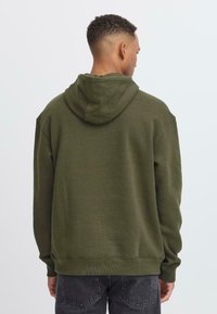 Olijfgroen hoodie met een ontspannen pasvorm, ribgebreide manchetten en onderrand, zachte textuur en een eenvoudig ontwerp. Geen zichtbare logo's of patronen.