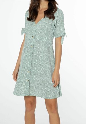 Mintgrünes Kleid mit weißem Blumenmuster, kurzen Ärmeln mit Bindebändern, V-Ausschnitt und vorderen Knöpfen. A-Linie und leichter Stoff.