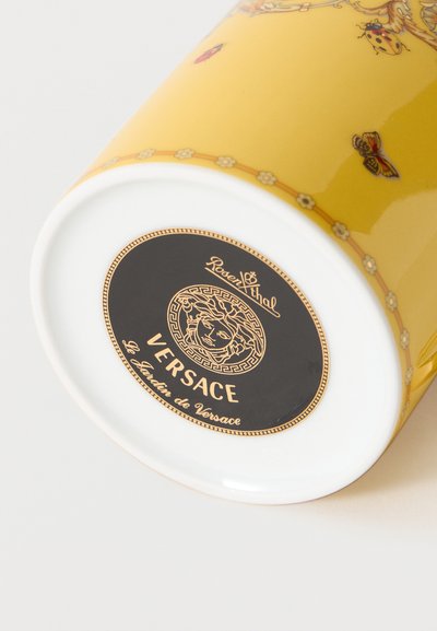 Κίτρινη κεραμική κούπα Versace με σχέδια πεταλούδας και πασχαλίτσας, με το μαύρο και χρυσό λογότυπο Rosenthal στη λευκή βάση.