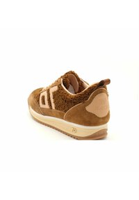 Des baskets marron avec une tige texturée et douce, des accents en daim et une semelle intermédiaire blanche. Présentent un branding minimaliste et un col rembourré.