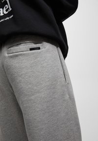 Grijze sweatpants van zacht katoen met een slim fit, voorzien van een externe zak met een zwart label en subtiele stiksels.