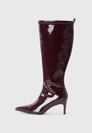 Stivali stiletto alti fino al ginocchio in pelle verniciata bordeaux con punta affusolata e design aderente. Presenta un anello laterale per una facile vestibilità.