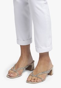 Beige sandaaltjes met hakken, voorzien van een blokhak, met kruislings straps versierd met rhinestones en een gladde, textuurafwerking.