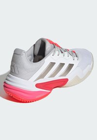 Zapatillas deportivas con una parte superior de malla gris, acentos plateados y una suela de goma rosa. Punta redondeada y cuello acolchado para mayor comodidad. Diseño texturizado.