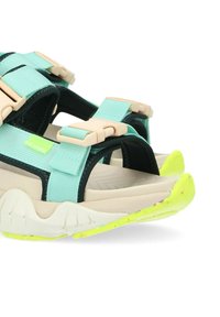 Sandali sportivi con tomaia nera e menta, cinturini regolabili e suola beige chiaro con grip testurizzato e accenti giallo neon.