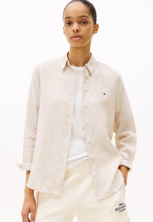 Beige gestreept overhemd met knopen, gemaakt van zachte stof en met een kraag, met een klein logo op de borst en met knoopmanchetten. Draag het over een wit shirt.