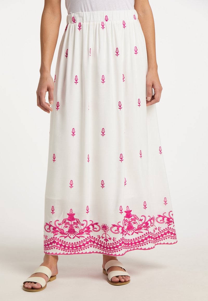 Fustă maxi albă cu broderie florală roz, talie elastică și design detaliat la margine. Purtată cu sandale de culori deschise.