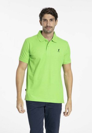 Polo en coton vert vif avec des manches courtes, un col, et un petit logo noir sur la poitrine. Assorti avec un pantalon sombre.